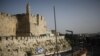 Beberapa pemuda membawa bendera Israel saat berjalan di dekat tembok yang mengelilingi Kota Tua Yerusalem, dalam pawai menandai Hari Yerusalem, di tengah ketegangan Israel-Palestina, 10 Mei 2021. (REUTERS/Nir Elias)