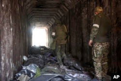 Prajurit milisi Republik Rakyat Donetsk melihat mayat tentara Ukraina yang ditempatkan dalam kantong plastik di sebuah terowongan, bagian dari Pabrik Metalurgi Pekerjaan Besi & Baja Illich di Mariupol. (Foto: AP)