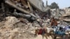 A Palestinian man rides a horse-pulled cart, next to a destroyed building where personal belongings of people and a car are sandwiched between the layers of its rubble, in Gaza City on Nov. 2, 2024.