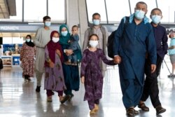 Families evacuated from Kabul, Afghanistan, walk through the terminal before boarding a bus after they arrived at Washington Dulles International Airport, in Chantilly, Va., Aug. 23, 2021.