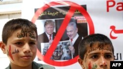 Palestinian children stand in front of a banner bearing the crossed out images of President Trump and Israeli PM Netanyahu during a protest against a US-led meeting this week in Bahrain on the Palestinian-Israeli conflict, June 24, 2019.