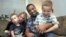Damon Brown sits with his wife, Bethany, as they hold their sons Theo, 3, left, and Julian, 5, at their home in Seattle. Damon Brown found a kidney on Facebook after telling his story on a special page the Seattle dad created under the name, “Damon Kidney