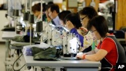 FILE - A group of workers at the C.C. Filson Co. manufacturing facility work at their sewing machines, in Seattle, Aug. 31, 2016.