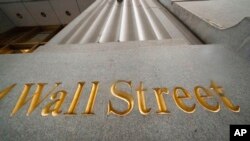 FILE - In this Nov. 5, 2020, photo, a sign for Wall Street is carved in the side of a building. U.S. stocks set records Jan. 20, 2021, on stronger-than-expected earnings reports and continued optimism that an economic recovery is on the way.
