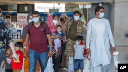 Families evacuated from Kabul, Afghanistan, walk through the terminal to board a bus after arriving at Washington Dulles International Airport, in Chantilly, Virginia, Aug. 28, 2021.
