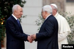 FILE - Israeli President Shimon Peres shakes hands with Palestinian President Mahmoud Abbas as Pope Francis looks on after a prayer meeting at the Vatican, June 8, 2014.