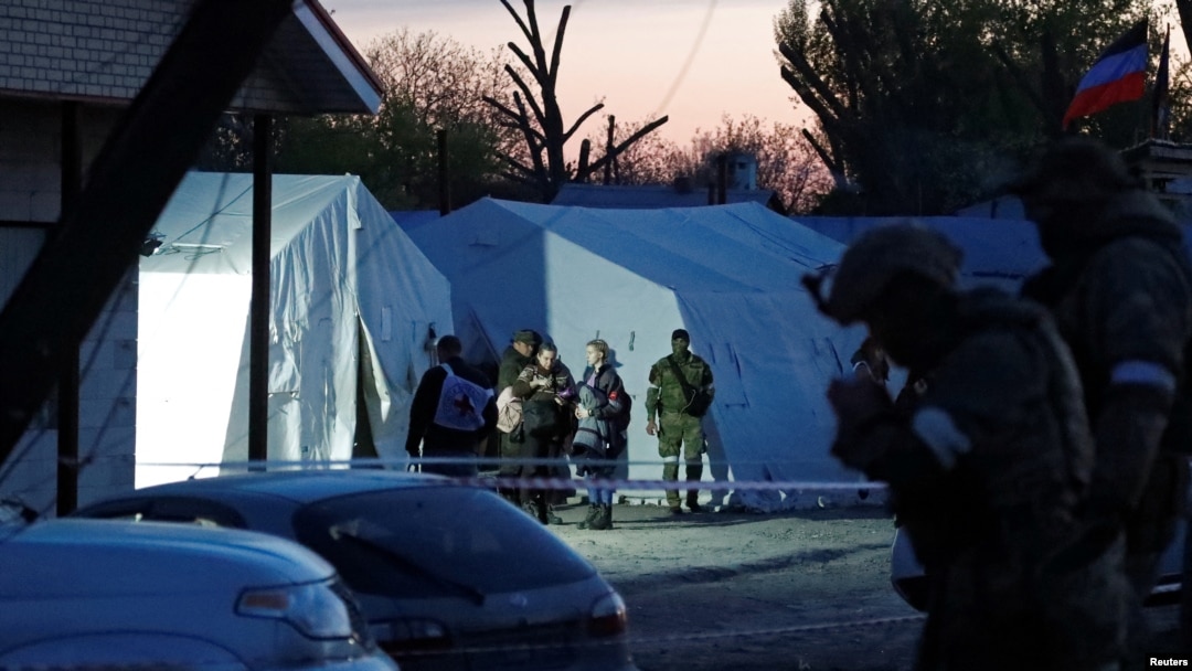 Sejumlah perempuan yang dievakuasi dari pabrik baja Azovstal di Mariupol berdiri dekat tentara pro Rusia di tempat penampungan sementara di Desa Bezimenne di tengah konflik Ukraina-Rusia di Wilayah Donetsk, Ukraina, Jumat, 6 Mei 2022. (Foto: Alexander Ermochenko/Reuters)
