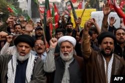 FILE - Shiite Muslims hold placards and shout slogans during a protest march against the sectarian attacks in Kurram district in Parachinar, the mountainous Khyber Pakhtunkhwa province, in Lahore, Pakistan, Nov. 22, 2024.