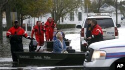 Regu penyelamat mengevakuasi Elaine Belviso, 72, yang terperangkap semalaman akibat hantaman badai Sandy di wilayah Babylon, New York, Selasa (30/10).