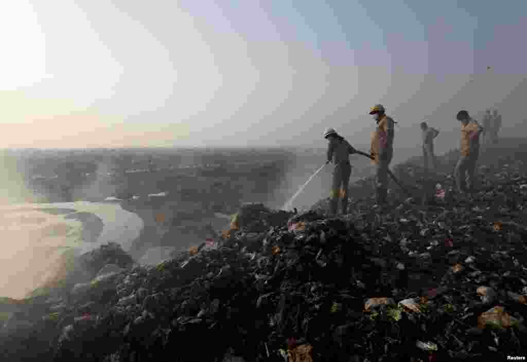 인도 델리의 발수와 쓰레기 매립지에서 소방관들이 타고 있는 폐기물에서 나는 연기를 소화기로 끄고 있다.