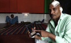 Manzoor Alam, a Muslim laborer, shows BJP MP Arjun Singh’s Facebook post. Alam was beaten by a Hindu mob in Telinipara. Singh posted a photo of bloodied Alam on Facebook and said he was a Hindu who had been beaten by Muslims. (Shaikh Azizur Rahman/VOA)