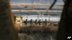 South Korean army soldiers patrol along a barbed-wire fence near the border village of Panmunjom in Paju, South Korea, Mar. 27, 2013. 