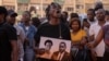 A man reacts as he holds an image of Paulo Guambe,left, and Elvino Dias, both associated with Mozambique's opposition party PODEMOS, during a vigil the day after they were shot dead in Maputo, Mozambique, Oct. 19, 2024.