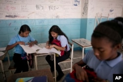 Maria Arias, center, works with classmates during a math class at her public high school in Caracas, Venezuela, June 1, 2016.