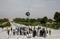 FILE - Chief Minister of Sindh province Syed Murad Ali Shah and Governor of Sindh province Imran Ismail along with officials raise the national flag during a ceremony to celebrate Pakistan's 73rd Independence Day, Aug. 14, 2020.