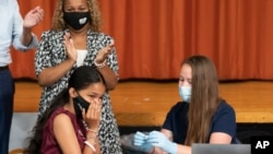 FILE - A high school student reacts after getting a COVID-19 vaccine shot in New York City, July 27, 2021. 