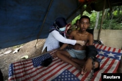 A doctor checks the health of Deden, a teenager whose father says suffers from mental illness and lives chained to a tree next to a rice paddy near his home in Longkewang village in Serang, Banten province, Indonesia, March 23, 2016.