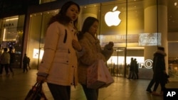 12月13日购物者走过北京商业区的一个苹果店。（美联社）