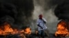 A protester demanding justice for the assassinated President Jovenel Moise stands near a burning barricade in Cap-Haitien, Haiti, July 22, 2021.