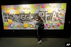 FILE - In this Nov. 14, 2019, photo, a student attaches a note to the Resilience Project board on the campus of Utah Valley University. (AP Photo/Rick Bowmer)