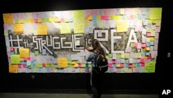 FILE - In this Nov. 14, 2019, photo, a student attaches a note to the Resilience Project board on the campus of Utah Valley University, in Orem, Utah. The purpose of the project is to let students know that it is OK to struggle.