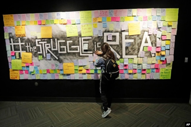 FILE - In this Nov. 14, 2019, photo, a student attaches a note to the Resilience Project board on the campus of Utah Valley University. (AP Photo/Rick Bowmer)