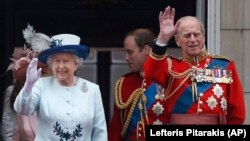 FILE - In this Saturday, June 14, 2014 file photo, Britain's Queen Elizabeth II, accompanied by Prince Philip, wave to the crowds from the balcony of Buckingham Palace, during the Trooping The Colour parade, in central London.