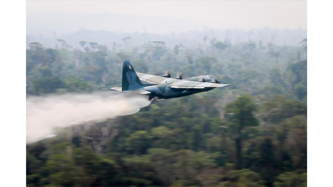 In a photo released by Brazil's Ministry of Defense, a C-130 Hercules aircraft dumps water to fight fires burning in the Amazon rainforest, in Brazil, Aug, 24, 2019.