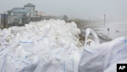 Karung pasir super ditempatkan di bagian atas tanggul "burrito" yang terbuka dan rusak sebagai persiapan menghadapi gelombang badai Delta Badai di Grand Isle, Kamis, 8 Oktober 2020. (Foto: AP)