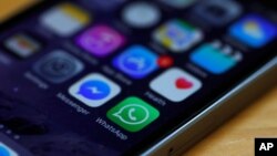 FILE - A WhatsApp icon (bottom, center) is seen on an iPhone in this March 27, 2017, illustration photo. WhatsApp is among the services subject to Uganda's new social media tax.