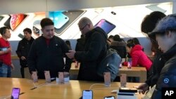 People buy latest iPhone while others try out its latest model at an Apple Store in Beijing, Tuesday, Dec. 11, 2018. (AP Photo/Andy Wong)