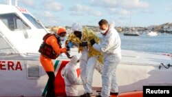 Petugas penjaga pantai Italia menolong seorang migran yang selamat mendarat di Pulau Lampedusa (11/2).