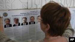 A polling station official hangs a list of candidates for the 2018 Russian presidential election, during preparations at a polling station in Simferopol, Crimea, March 17, 2018. Russian voters, observers and eight presidential candidates are gearing up for an election that will undoubtedly hand Vladimir Putin another six-year term.