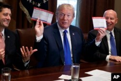 FILE - President Donald Trump holds an example of what a new tax form may look like during a meeting on tax policy with Republican lawmakers, Nov. 2, 2017.