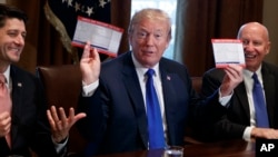 President Donald Trump holds an example of what a new tax form may look like during a meeting on tax policy with Republican lawmakers including House Speaker Paul Ryan of Wis., and Chairman of the House Ways and Means Committee Rep. Kevin Brady, R-Texas, right, in the Cabinet Room of the White House, Thursday, Nov. 2, 2017, in Washington. 