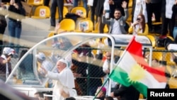 A Kurdistan flag is held up as Pope Francis arrives to hold a mass at Franso Hariri Stadium in Erbil, Iraq, March 7, 2021. 