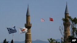 (From left to right) Greek and Cyprus' flags, a Turkish and Turkish Cypriot breakaway flags fly on a minaret of the Selimiye mosque, or Cathedral of St Sophia in divided capital Nicosia, Cyprus, April 26, 2021.