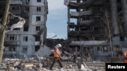 A clean up worker walks past buildings that were destroyed by Russian shelling, in Borodianka, in the Kyiv region, Ukraine, April 7, 2022. REUTERS/Marko Djurica 