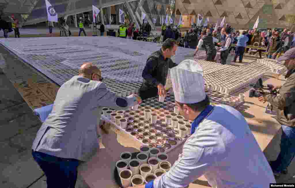 Stewards and volunteers placed the prepared coffee cups in marked holders to replicate the mask. (H. Elrasam/VOA)