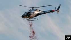 Un helicóptero arroja pétalos de rosas en honor de las víctimas en el lugar del desastre.