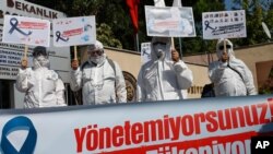 Health workers and doctors wearing personal protective equipment hold a protest against the Turkish goverment's health policy in front of Istanbul University medical faculty, Sept. 15, 2020. 