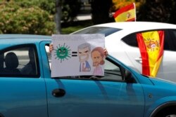 FILE - A demonstrator holds a sign depicting Spanish PM Pedro Sanchez and Deputy PM Pablo Iglesias during a drive-in protest organied by Spain's far-right party Vox against the government's handling of COVID-19, May 23, 2020.
