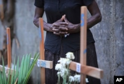 FILE - A Sri Lankan relative of a victim of Easter Sunday bomb blasts pays tribute at the burial site after a televised Sunday Mass by Sri Lankan Archbishop Cardinal Malcolm Ranjith, in Negombo, north of Colombo, Sri Lanka, April 28, 2019. Sri Lankan churches were shut across the island nation shut over fears of militant attacks, a week after the Islamic State-claimed Easter suicide bombings killed over 250 people.