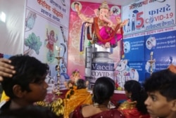 Para penyembah mengantre untuk berdoa kepada patung Dewa Hindu Ganesha di tenda bertema COVID-19 saat dimulainya festival Ganesh Chaturthi selama sepuluh hari di Mumbai, India, 10 September 2021. (REUTERS /Francis Mascarenhas)