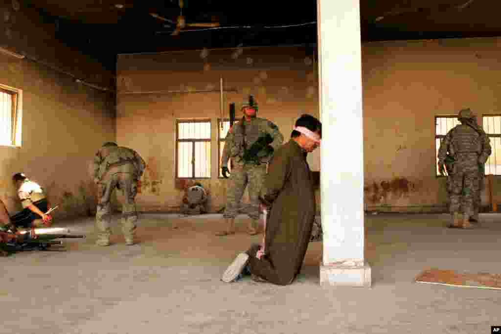 یک سرباز عراقی از یک مرد که پس از درگیری مسلحانه در مرکز بعقوبه در عراق بازداشت شده بود، محافظت می کند. ٢٠ مارس سال ٢٠٠٧.