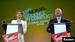 Actress and special envoy of the UN High Commissioner for Refugees (UNHCR), Angelina Jolie, and British Foreign Secretary William Hague make their opening speeches at a global summit to end sexual violence in conflict in London, June 10, 2014. 