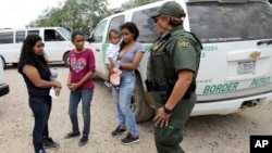U.S. Border Patrol agent-in-charge Melissa Lucio, right, talks with women and children migrating from Honduras after they surrendered to U.S. Border Patrol agents after illegally crossing the border Monday, June 25, 2018, near McAllen, Texas. (AP Photo/Da