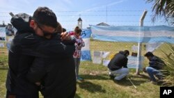 Relatives and friends of Alejandro Tagliaprieta, a crew member on the missing ARA San Juan submarine, embrace at the naval base where people hang flags and messages on the fence in Mar de Plata, Argentina, Nov. 24, 2017.