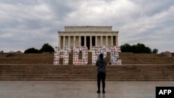 কোভিড-১৯ মহামারীতে চ্যালেঞ্জের সম্মুখীন হওয়া ফ্রন্ট লাইন কর্মীদের সম্মান জানাতে লিঙ্কন মেমোরিয়ালের সামনে ‘হোপ’ চিহ্নের ছবি তুলছেন একজন দর্শক। ওয়াশিংটন ডিসি। ৬ মার্চ,২০২২।