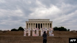 FILE - A visitor takes a photo of a 'Hope' sign, displayed in front of the Lincoln Memorial in Washington, DC, on March 6, 2022, to honor frontline workers who have faced challenges through the Covid-19 pandemic. 